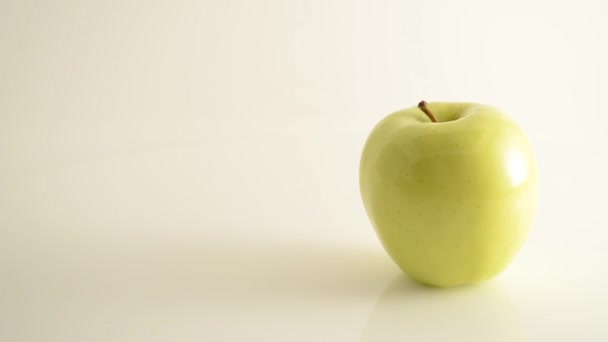 Rotating Golden Delicious Apple On Acrylic Against White - Crane Down - Imágenes, Vídeo