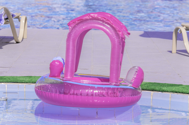 Anillo de plástico rosa flotando en una piscina
 - Foto, imagen