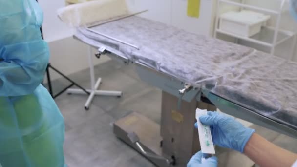Enfermeiros de perto em luvas e roupas estéreis preparam seringas e agulhas antes da cirurgia de escleroterapia
 - Filmagem, Vídeo