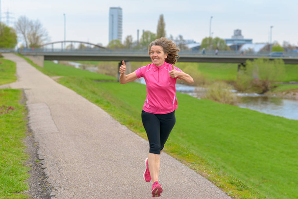 Щаслива жінка бігун показує великі пальці вгору
 - Фото, зображення