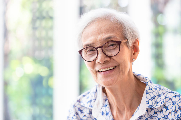 Close up asiático idosa mulher em óculos mostrando saudável em linha reta dentes, retrato sênior mulher sorrindo sentindo feliz, bela fêmea olhando para câmera em casa
 - Foto, Imagem