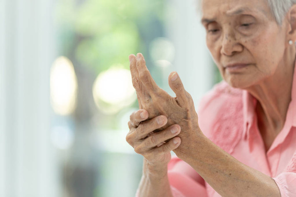 asiatische alte Frau massiert ihre eigene Hand, ältere Frau leidet unter Schmerzen in der Hand, Arthritis, Beriberi oder peripheren Neuropathien - Foto, Bild