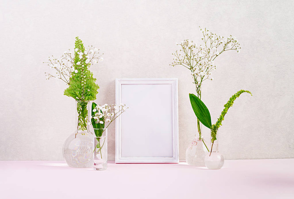 Flowers and plants in flask with frame. Beautiful spring background with flowers in vase. - Photo, Image