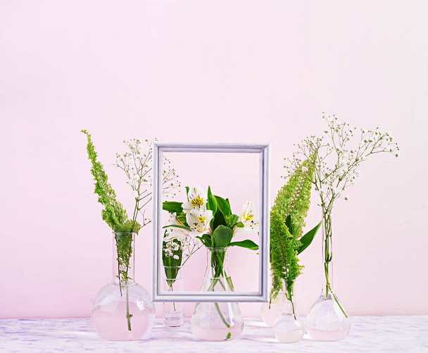 Квіти і рослини в колбі з рамою. Прекрасний весняний фон з квітами у вазі
. - Фото, зображення