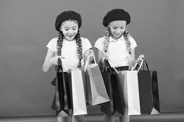 Kids cute schoolgirls hold bunch shopping bags. Children satisfied by shopping red background. Obsessed with shopping and clothing malls. Shopaholic concept. Shopping become fun with best friends - Photo, image