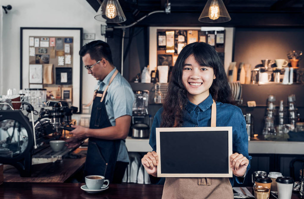 Asian female barista wear jean apron holding blank blackboard co - Foto, Imagem