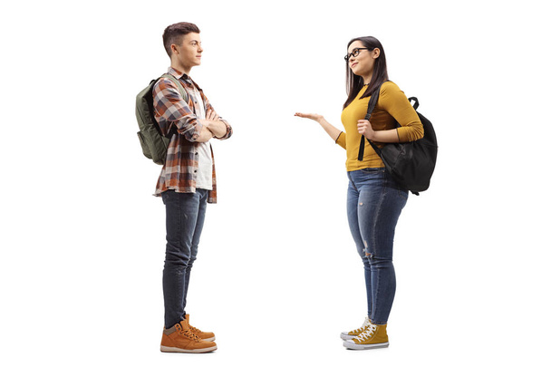 Full length profile shot of female student talking to a male student friend isolated on white background - Foto, immagini