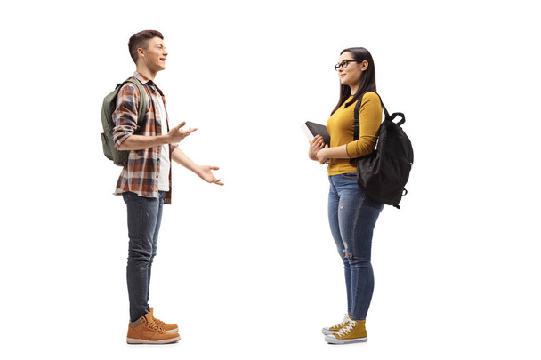 Full length profile shot of male and female students talking isolated on white background - Fotoğraf, Görsel
