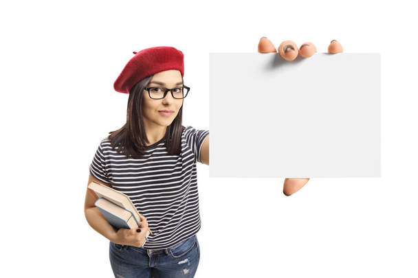 Young brunette female holding books and a blank card isolated on white background - Fotó, kép
