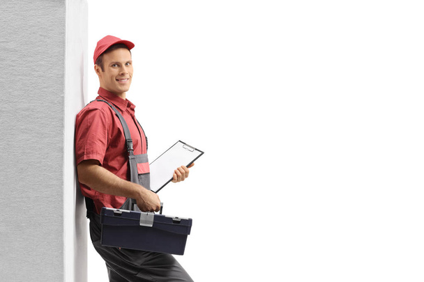 Handyman with a toolbox leaning against wall isolated on white background - Fotó, kép