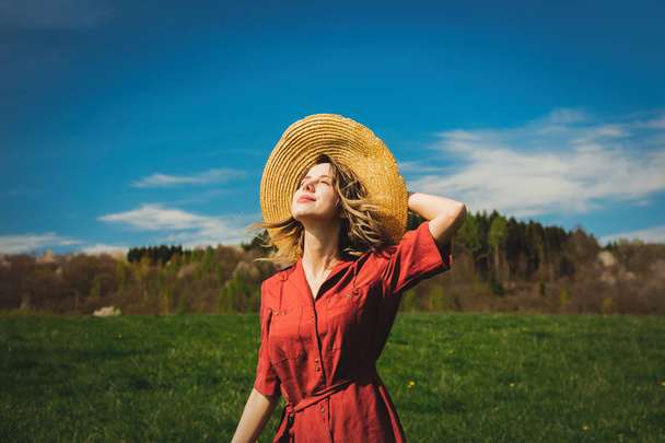 Hermosa chica en vestido rojo y sombrero tienen un tiempo despreocupado en el aguamiel
 - Foto, Imagen