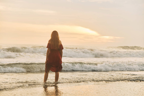 Beautiful sunset. Silhouette of young woman walking on ocean beach. - Zdjęcie, obraz