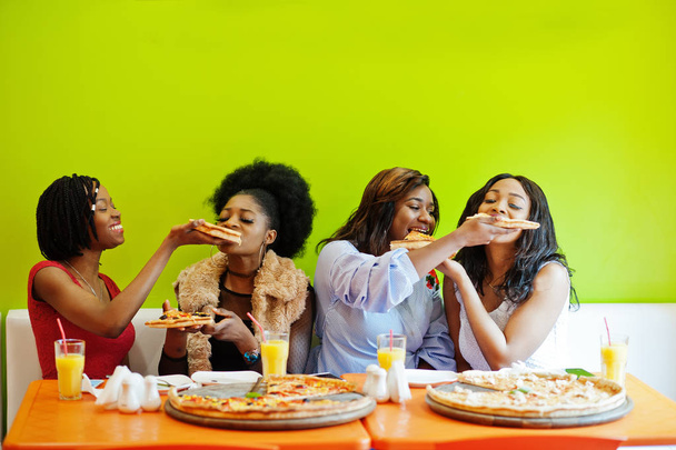 ピズを食べる明るい色のレストランで4人の若いアフリカの女の子 - 写真・画像