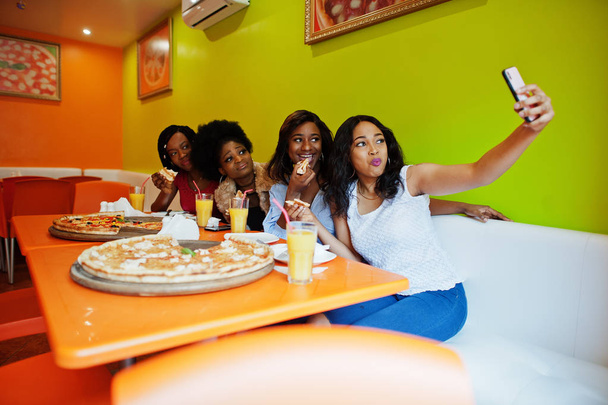 Four young african girls in bright colored restaurant eating piz - Photo, Image