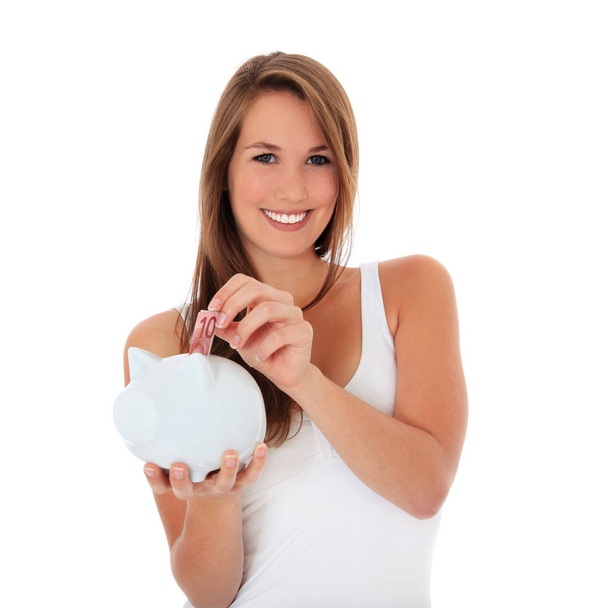 Attractive young woman puts money in piggy bank. All on white background. - Photo, Image
