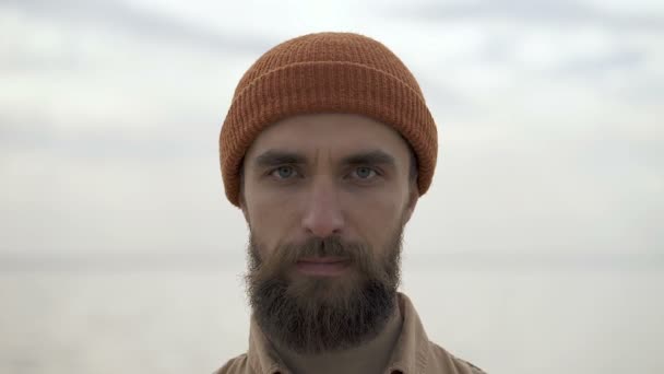 Portrait of no emotional, concentrated beard man looking at camera. Outdoors near the sea. - Imágenes, Vídeo