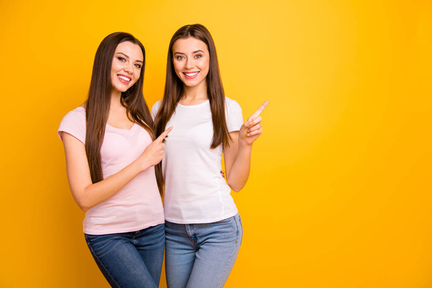 Close up photo two people beautiful she her ladies models best buddies hand arm fingers indicate direct empty space cool offer black friday wear white pink casual t-shirts isolated yellow background - Photo, image