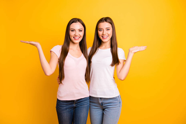 Close up photo two people beautiful she her ladies models best buddies hand arm palms open indicate empty space black friday opportunity wear white pink casual t-shirts isolated yellow background - 写真・画像