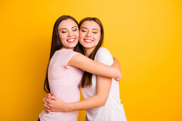 Close up side profile  photo two people beautiful she her ladies models full emotions feelings fellowship buddies hugging eyes closed wear white pink casual t-shirts isolated yellow background - Foto, imagen