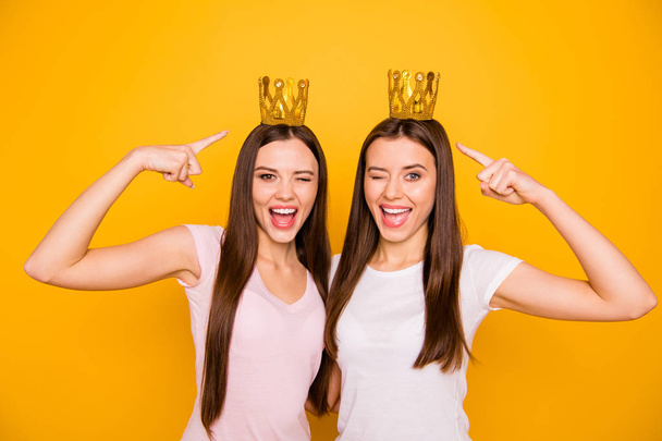 Portrait of nice-looking cute charming lovely sweet attractive cheerful cheery coquettish straight-haired girls showing crowns isolated over bright vivid shine yellow background - Foto, afbeelding