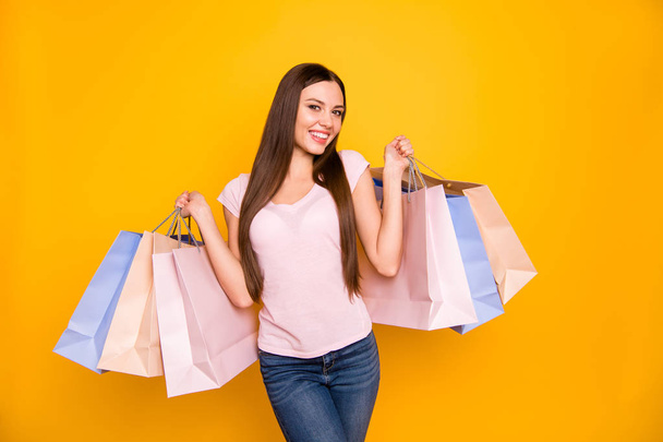 Portrait of her she nice cute charming lovely winsome sweet adorable attractive cheerful straight-haired girl holding in hands colorful bags isolated on bright vivid shine yellow background - Fotó, kép