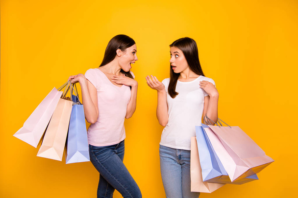 Portrait of nice cute charming girlish sweet attractive cheerful straight-haired teen girls holding in hands carrying new cool purchase isolated on bright vivid shine yellow background - Photo, Image
