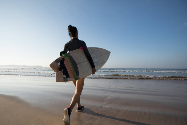 Woman surfer with surfboard going into sea - Foto, Imagem