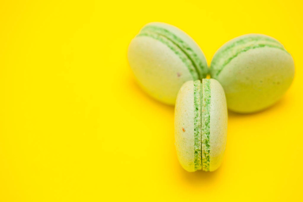 Słodkie i pyszne zielone makaroniki na żółtym tle - Zdjęcie, obraz