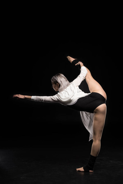 back view of woman in bodysuit dancing on black - Valokuva, kuva