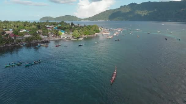 Aérea: kora-kora tradicional carrera anual en canoa en Bandaneira y lanchas rápidas navegando en el hermoso mar de las Islas Banda, Maluku, Indonesia. Perfil de color D-log cinelike nativo
 - Metraje, vídeo