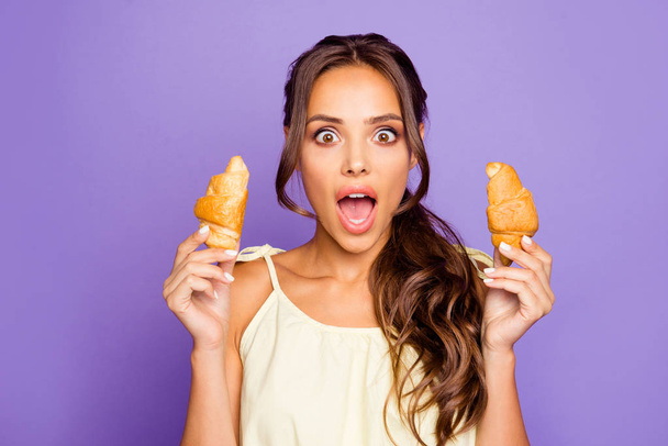 Close-up photo of pretty wondered expression funny funky face she her lady holding two small fresh homemade croissants with open mouth wants to bite isolated violet background - Valokuva, kuva