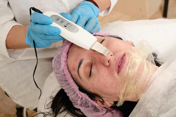 Mujer joven en el salón de belleza hace el procedimiento de pelado por ultrasonido y limpieza facial
. - Foto, imagen