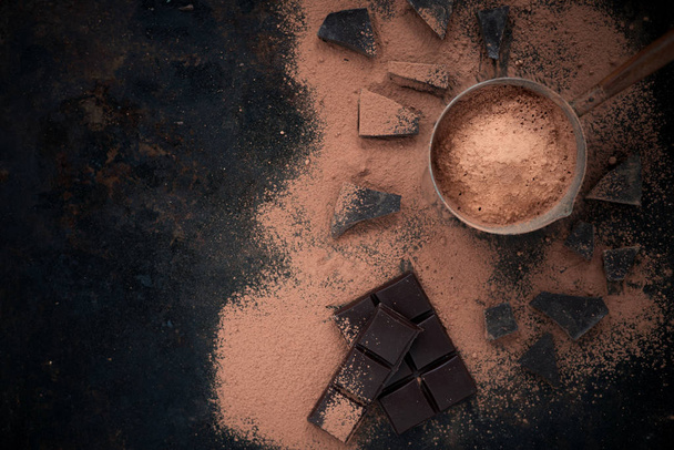 Chocolate on dark vintage background with cocoa powder.Top view.Copy space. - Φωτογραφία, εικόνα