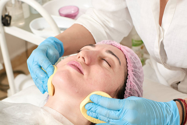 Молодая женщина в салоне красоты делает увлажняющую процедуру кожи после ультразвукового пилинга
. - Фото, изображение