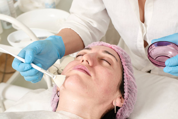 Νεαρή γυναίκα στο ινστιτούτο ομορφιάς κάνει ενυδάτωση του δέρματος διαδικασία μετά το υπερηχογράφημα ξεφλούδισμα. - Φωτογραφία, εικόνα