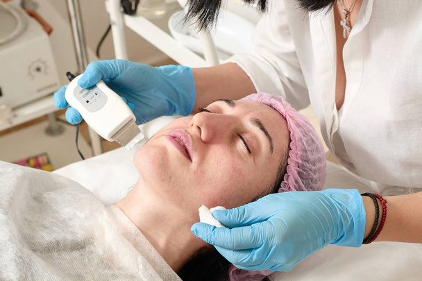 Mujer joven en el salón de belleza hace el procedimiento de pelado por ultrasonido y limpieza facial
. - Foto, Imagen