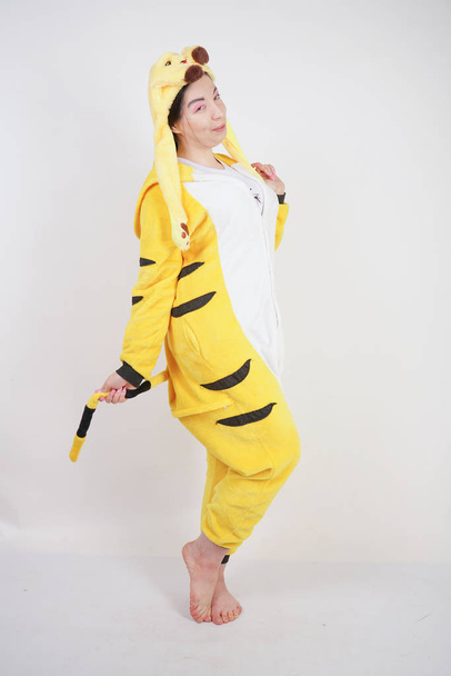 funny cheerful girl in big yellow pajamas kigurumi posing on a white background in the Studio - Zdjęcie, obraz