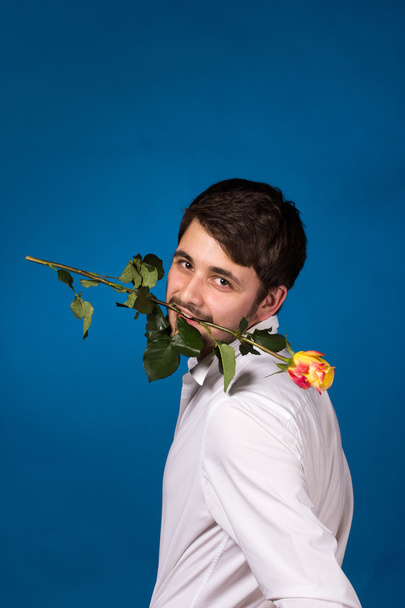 Young man holding a red rose in his mouth - Foto, Imagen