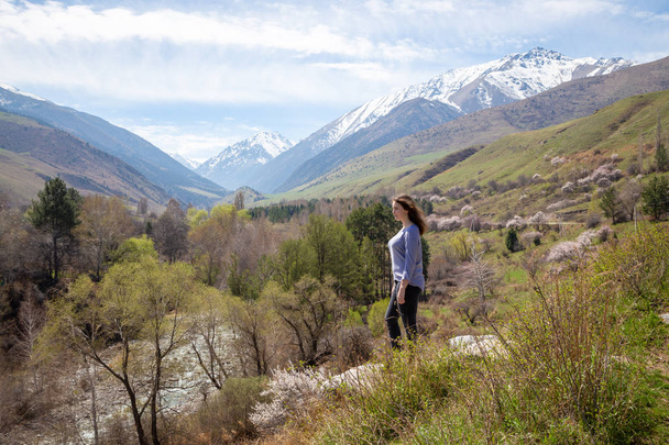 Νεαρή κοπέλα στο φόντο των ανοιξιάτικων βουνών. Όμορφο ορεινό φαράγγι. Φύση και περιπέτεια. - Φωτογραφία, εικόνα