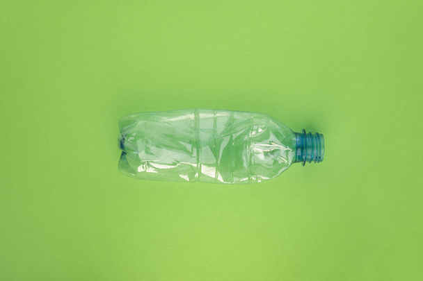 Crashed plastic bottle on green background. Plastic utilisation concept. Ecological problem, global environment. - Photo, image