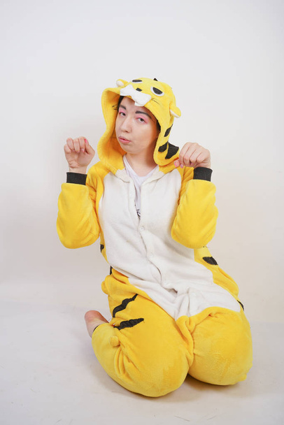 funny cheerful girl in big yellow pajamas kigurumi posing on a white background in the Studio - Photo, Image