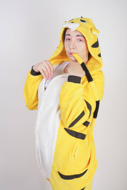 funny cheerful girl in big yellow pajamas kigurumi posing on a white background in the Studio - Foto, afbeelding
