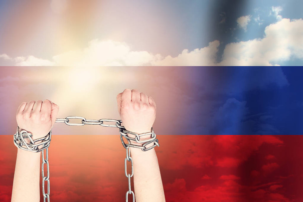 ロシア国旗の背景に金属チェーンを2本の手で縛った - 写真・画像