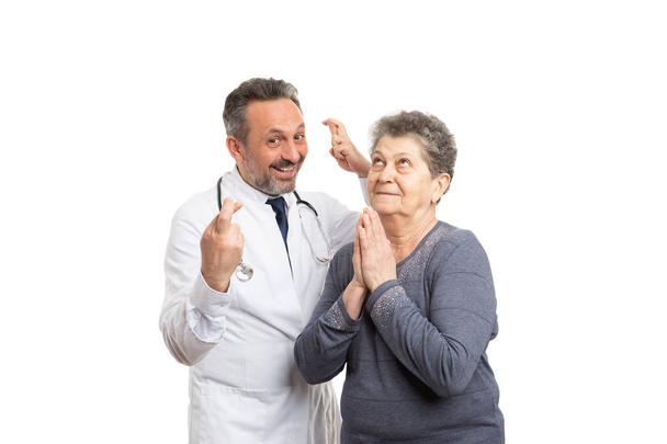 Lääkintämies sormet ristissä ja potilas rukoilee onnea
 - Valokuva, kuva
