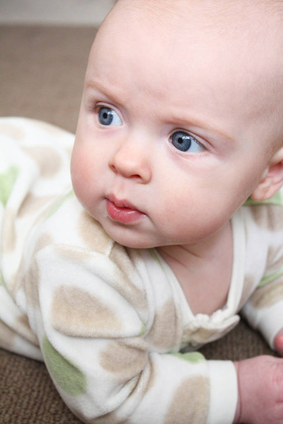 A close-up image of a baby playing on a brown carpet. - Photo, image