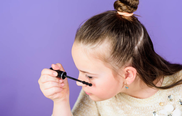 Giving her eyes some love. Little girl applying eye mascara. Small child using cosmetic for enhancing eye lashes. Adorable kid doing her eye makeup - Zdjęcie, obraz