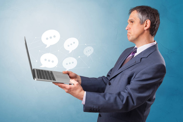 Man holding laptop with speech bubbles - Фото, изображение