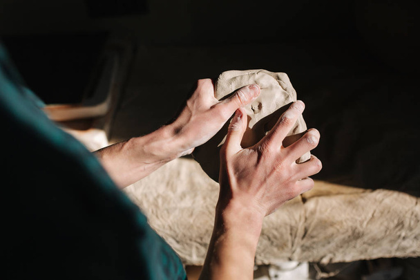 Close up of man works with clay. Male potter kneads and moistens the clay before work, toned - Photo, image