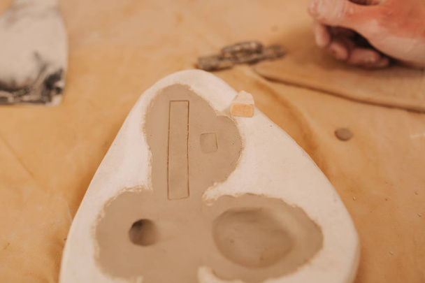 Timbro sulla farfalla di argilla. Prodotto ceramico. Mano dell'uomo sul tavolo
 - Foto, immagini