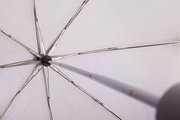 Close-up of an old grey umbrella, from the handle up - 写真・画像